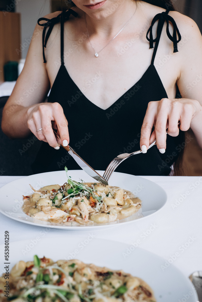 woman tasting Italian food in restaurant, woman hands holing  fork and knife eating food in restaurant
