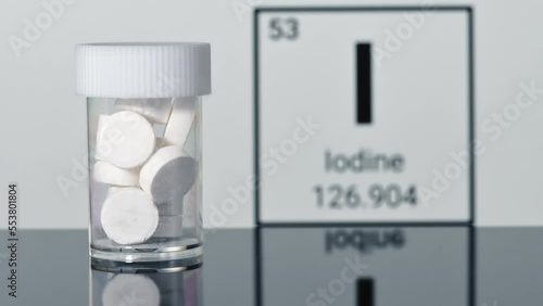 Man puts a jar with anti-radiation iodine pills on the table, chemical element of Iodine on the background photo