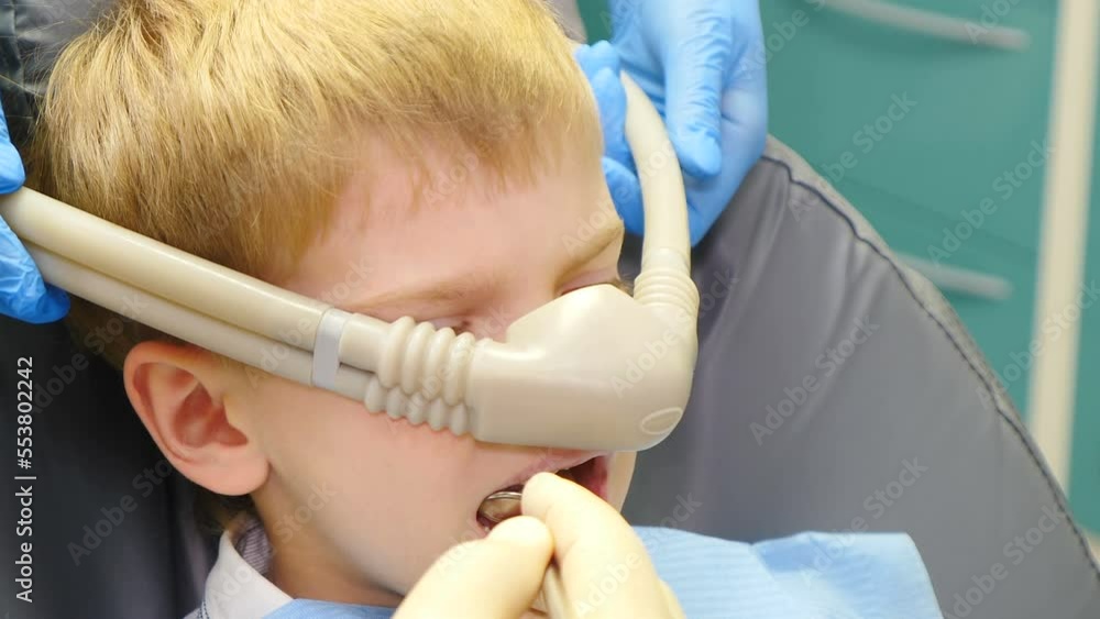 Dentist using nitrous oxide in dental clinic while treating young