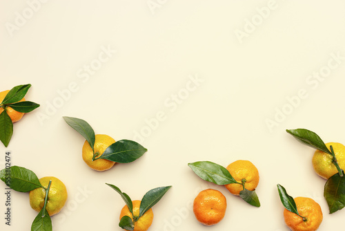Ripe fresh orange yellow tangerines with green leaves on pastel beige table background with copy space. Citrus fruit mandarines as food background, empty space, still life aesthetic photo photo