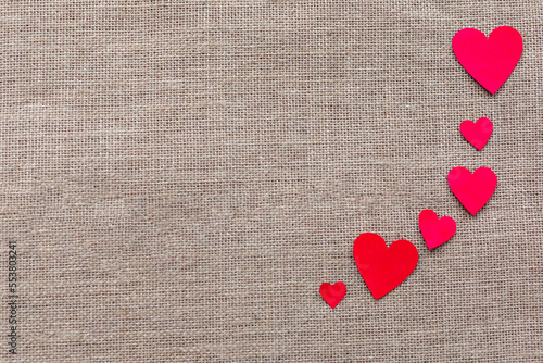 Paper craft hearts on a burlap background top view. Valentine background with many red hearts. Flat lay