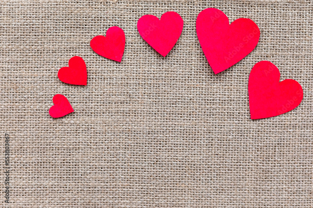 Paper craft hearts on a burlap background top view. Valentine background with many red hearts. Flat lay