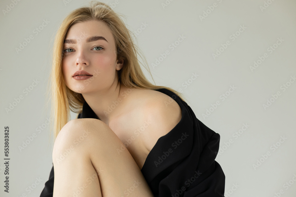 sensual blonde woman posing in black blazer and looking at camera isolated on grey. sensual blonde woman posing in black blazer and looking at camera isolated on grey.