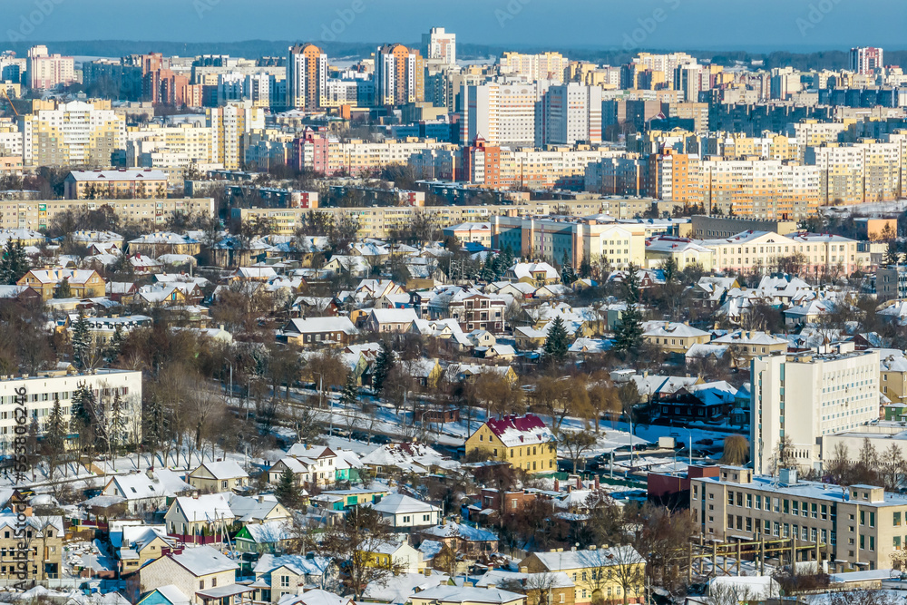 panoramic aerial view of a winter city with a private sector and high-rise residential areas with snow