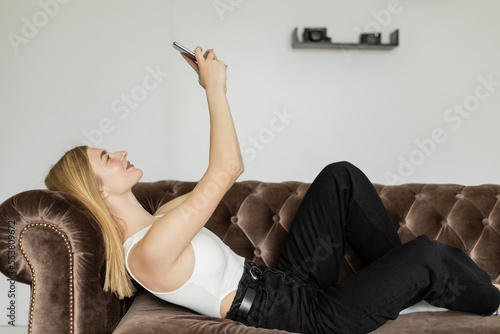 Side view of smiling blonde woman taking selfie on smartphone.