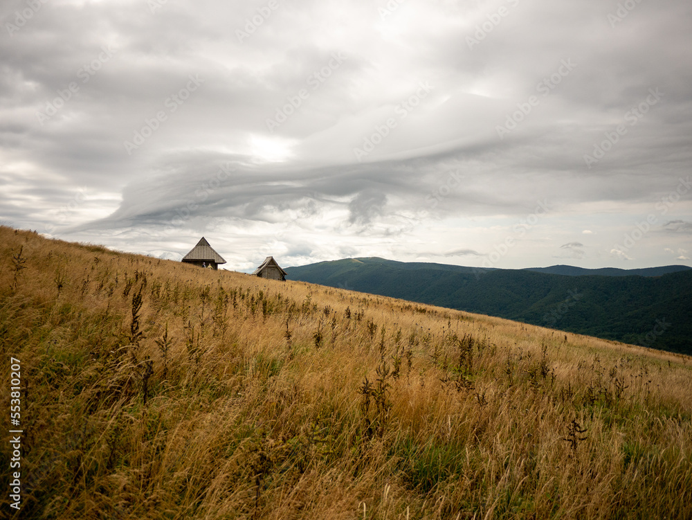 landscape in the mountains with two huts on the hill slope