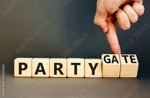 Party and partygate symbol. Concept words Party and Partygate on wooden cubes. Businessman hand. Beautiful grey table grey background. Business party and partygate concept. Copy space.