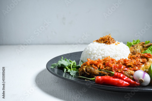 Ayam geprek sambal indonesian food or geprek fried chicken with sambal hot chili sauce served steam rice. Ayam Geprek is a typical Indonesian flour fried chicken dish that is pulverized or crushed photo