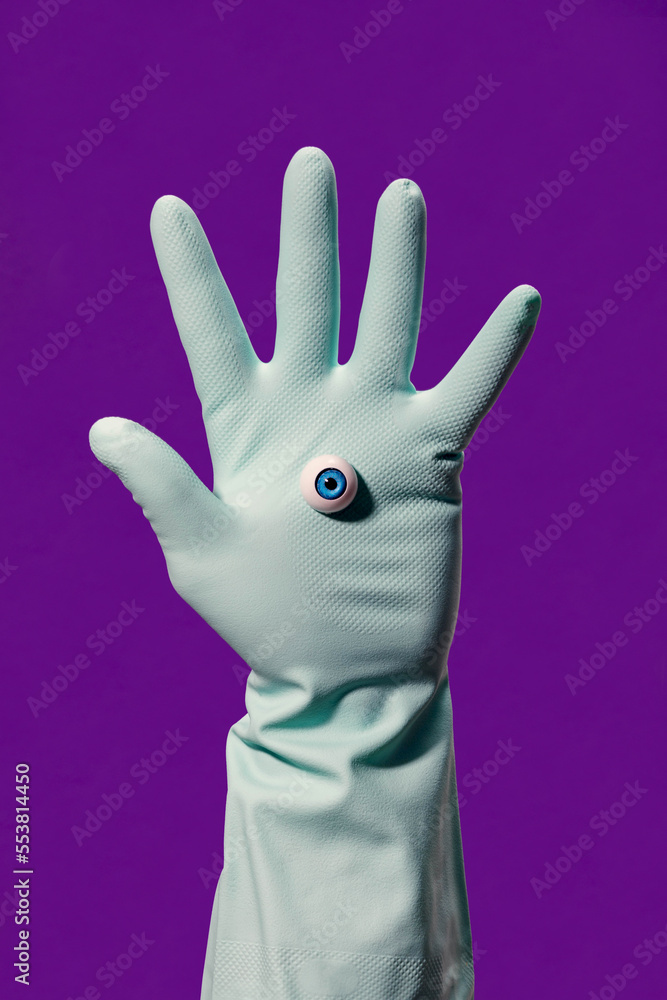 Crop person in glove with fake eye in violet studio Crop person in glove with fake eye in violet studio