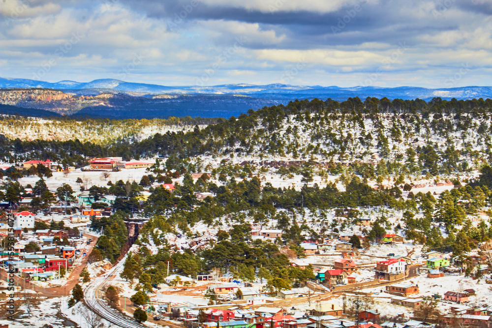 city surrounded by mountains on winter with snow covering pine trees, creel chihuahua