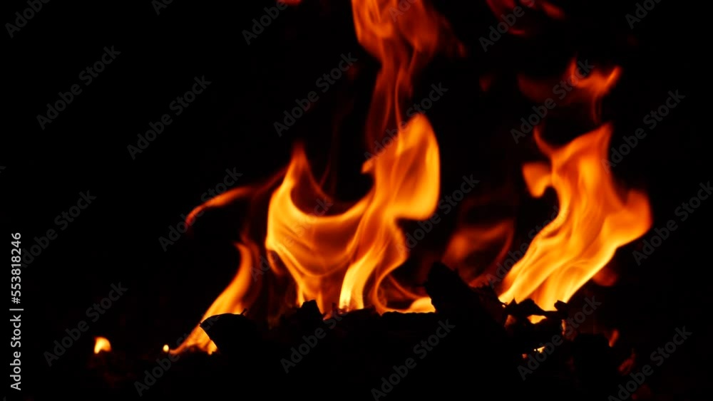 Fire burning vigorously orange and yellow flames behind substance on ground in the dark Fire burning vigorously orange and yellow flames behind substance on ground in the dark