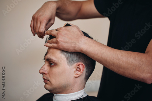 hairdresser does haircut for man in barber shop
