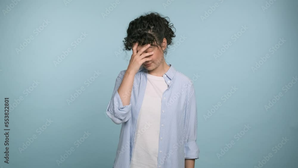 Sad upset confused brunette woman 20s put hand on face facepalm epic fail mistaken omg gesture isolated on blue background. People emotions lifestyle concept Sad upset confused brunette woman 20s put hand on face facepalm epic fail mistaken omg gesture isolated on blue background. People emotions lifestyle concept