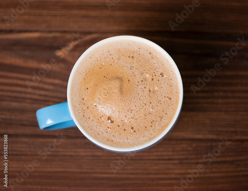 Blue cup with hot cocoa on wooden background top view