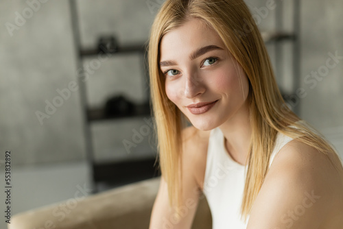 Portrait of blonde young woman smiling at camera at home.