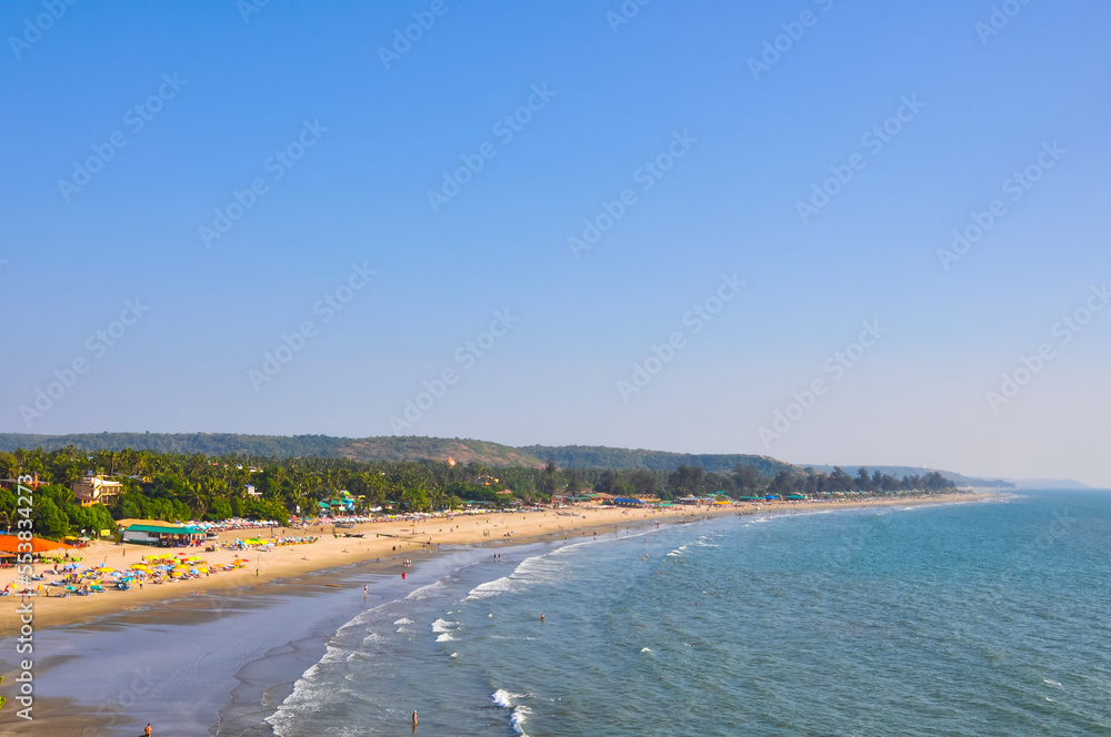 View from a distance on the beach with tourists in Arambol, Goa, India