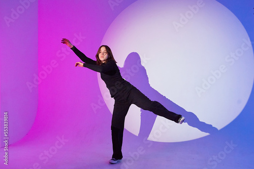 Teenage girl dances in a spotlight. The play of light and shadow.