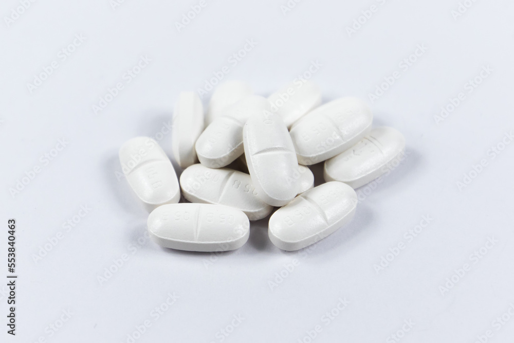 many white oval medical tablets for humans and animals, medicinal antibiotics pills medicine closeup
