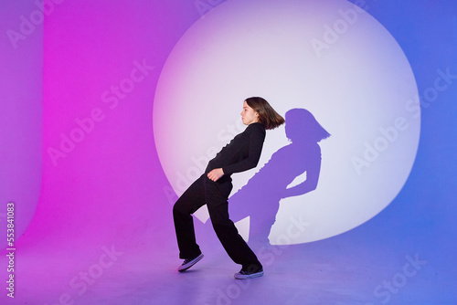 Teenage girl dances in a spotlight. The play of light and shadow.