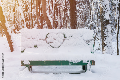 Heart painted on white fluffy snow on the back of the bench