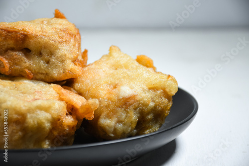 Selective Focus Gorengan or Fried tofu is a type of fried food made from tofu, flour and filled with bean sprouts on a black plate. Fried food is one of the favorite snacks in Indonesia.