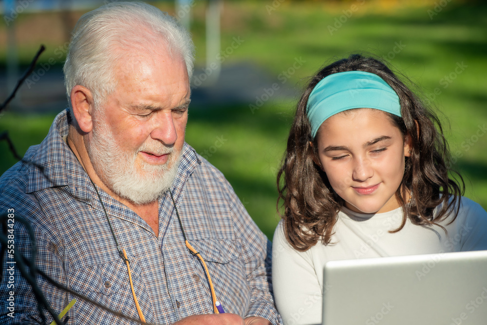 Grandfather explains how to use laptop to his granddaughter. Grandfather explains how to use laptop to his granddaughter.