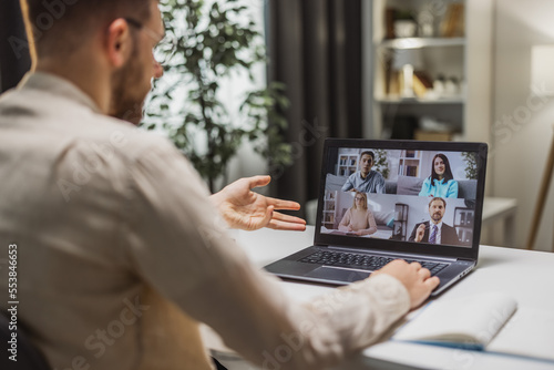 Backview of male having business conversation with colleagues from home, discussing business issues