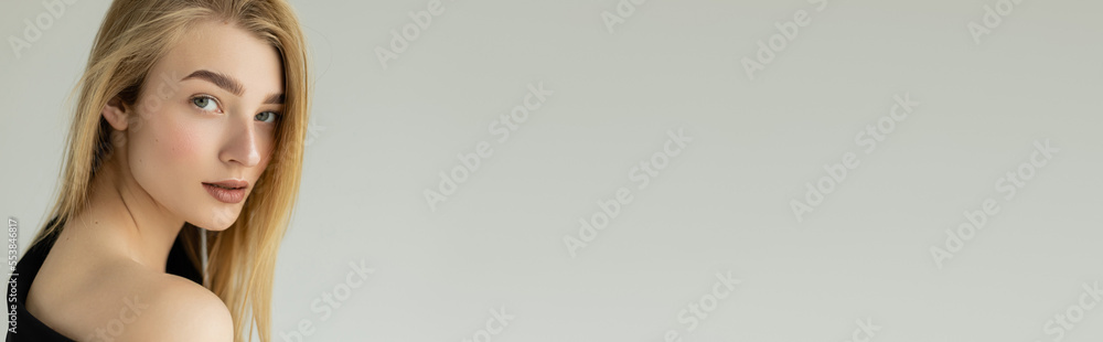 portrait of blonde woman with perfect skin and natural makeup looking at camera isolated on grey, banner. portrait of blonde woman with perfect skin and natural makeup looking at camera isolated on grey, banner.
