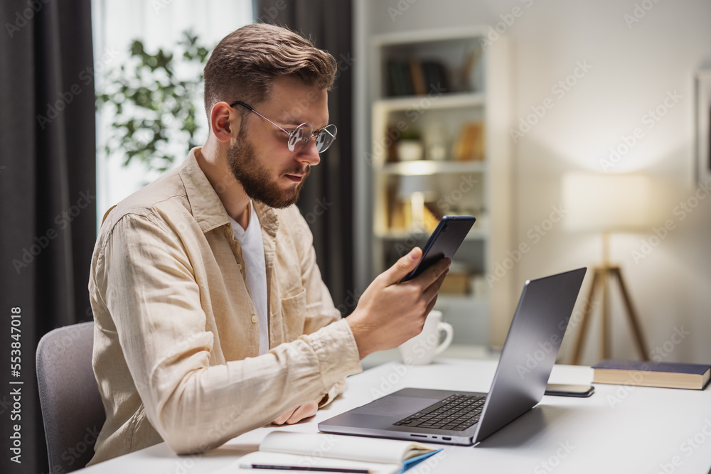 Businessman working from home, checking messages on the smartphone. Staying in touch with colleagues. Businessman working from home, checking messages on the smartphone. Staying in touch with colleagues.