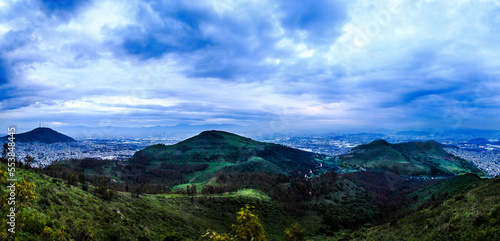 green mountains in blue hour surrounded by city on cloudy day, sierra de guadalupe with state of mexico and mexico city in the background  photo