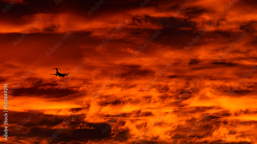 Black airplane in the dramatic orange sky.