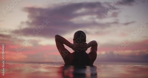 Close up of beautiful woman emerging from the water of luxury resort pool at sunset, relaxing health and wellness spa vacation