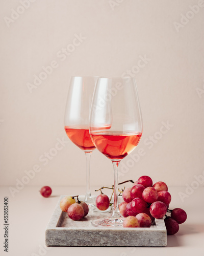 Two glasses of rose wine and red grapes.
