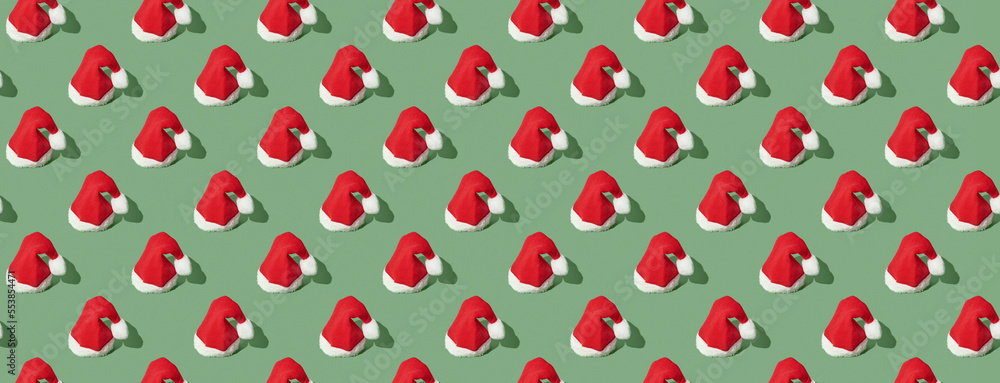 Pattern of christmas hats on green pastel background