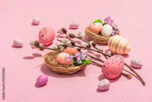 Traditional Easter composition - eggs, bird's nests, willow twigs, themed decor. Pink background