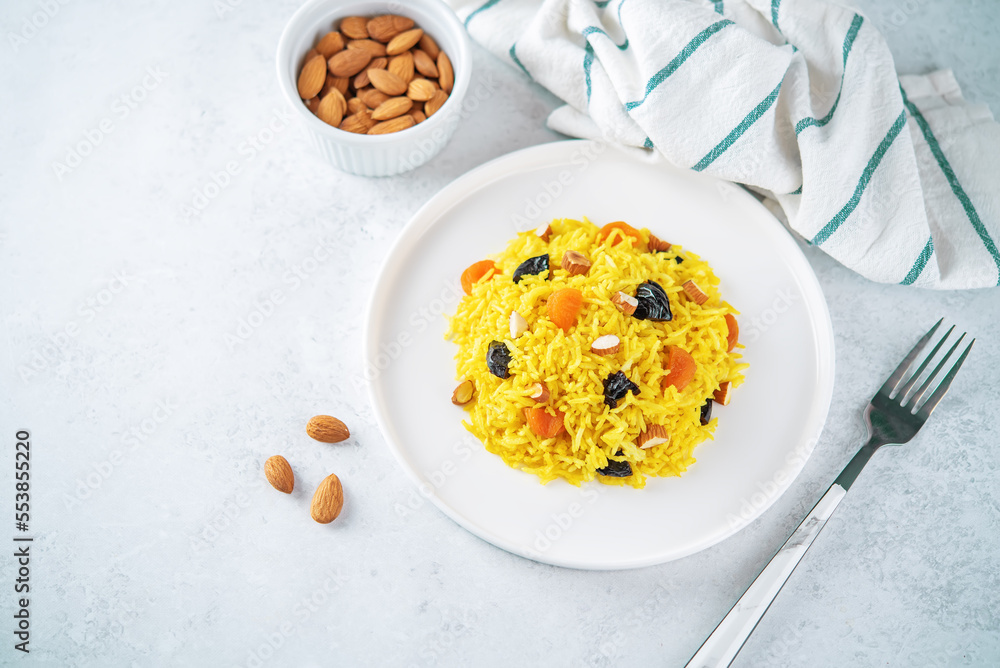 Turmeric basmati rice with dried apricots and prunes and almonds in a plate Turmeric basmati rice with dried apricots and prunes and almonds in a plate