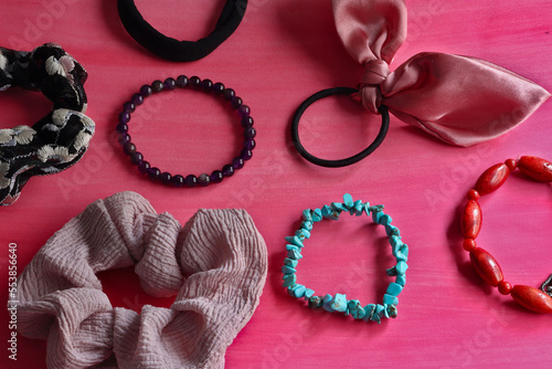 view of hair elastics of different shapes and colors on a pink background