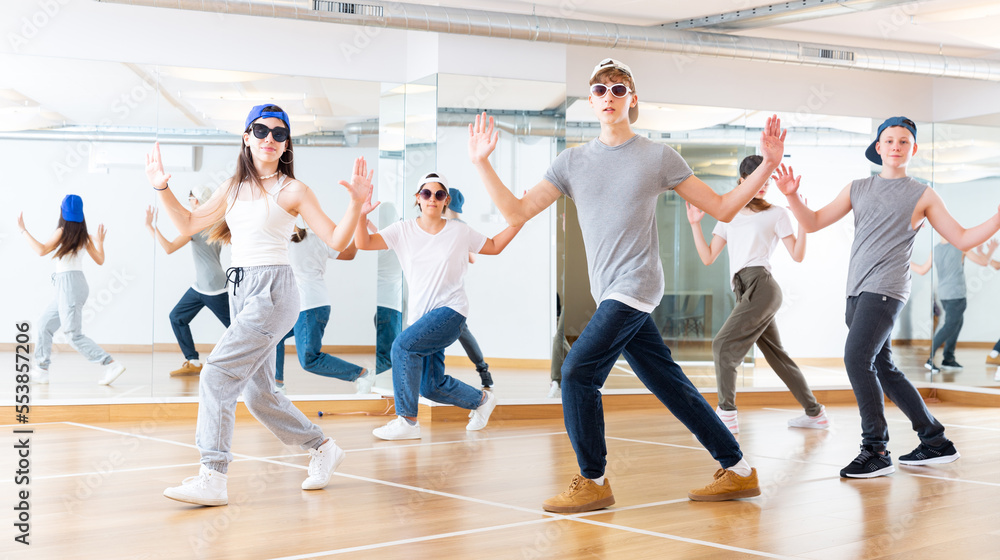 Focused teenage hip hop dancers doing dance workout during group class