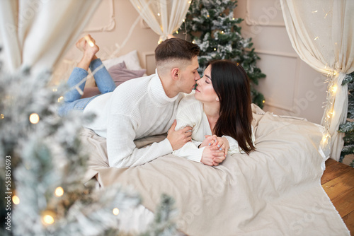 charming girlfriend feeling happiness being with her boyfriend and communicating with each other, positive romantic couple relaxing on bed during winter vacation at cozy home interior © Ryzhkov Oleksandr