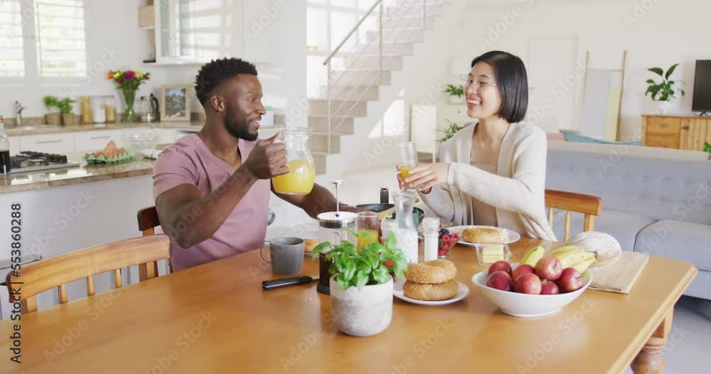 Happy diverse couple sitting at table and having breakfast Happy diverse couple sitting at table and having breakfast