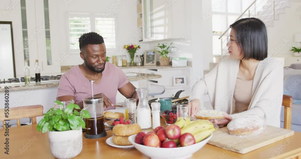 Happy diverse couple sitting at table and having breakfast Happy diverse couple sitting at table and having breakfast