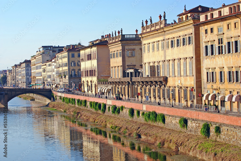 The late afternoon sun shines breightly on apartment buildings along the Arno river in Florence, Italy.