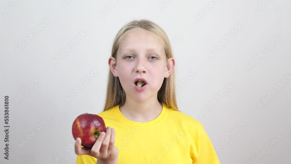 portrait of a cute little girl biting and eating a ripe red apple, looking at the camera on a white background. Healthy food and beauty. diet portrait of a cute little girl biting and eating a ripe red apple, looking at the camera on a white background. Healthy food and beauty. diet