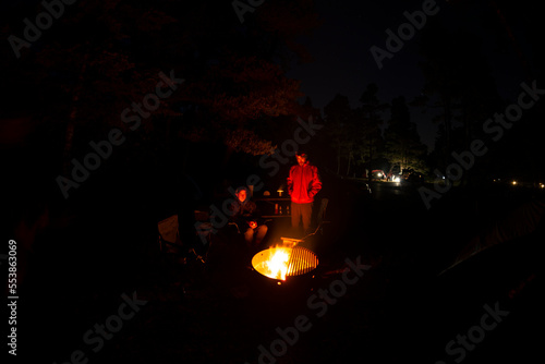 Adventurous athletic men sitting around a campfire, at their camp at night. 