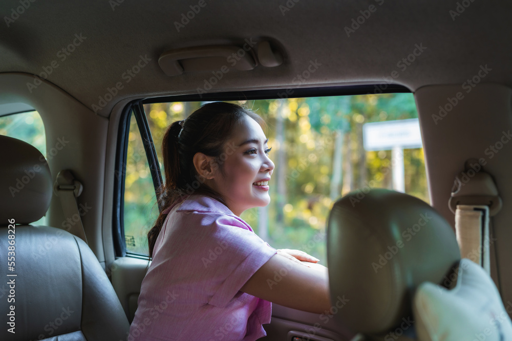 Beautiful Asian woman enjoying looking out of the window's car while having a road trip
