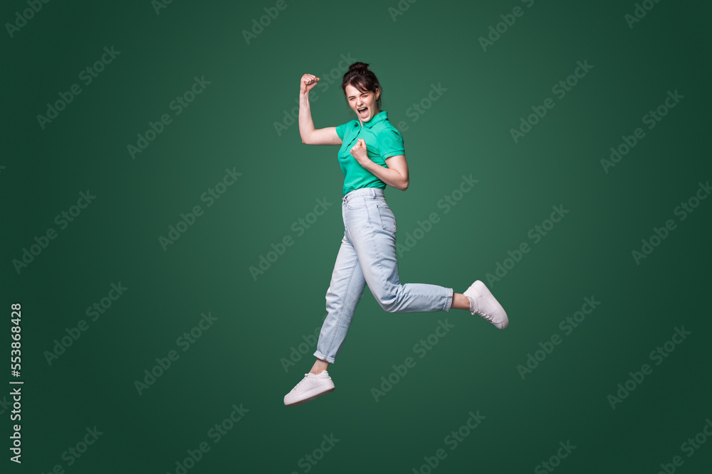 Full size profile photo of brunette lady running celebrating favorite team victory isolated on green background. Happiness, win, success. Full length. Full size profile photo of brunette lady running celebrating favorite team victory isolated on green background. Happiness, win, success. Full length.