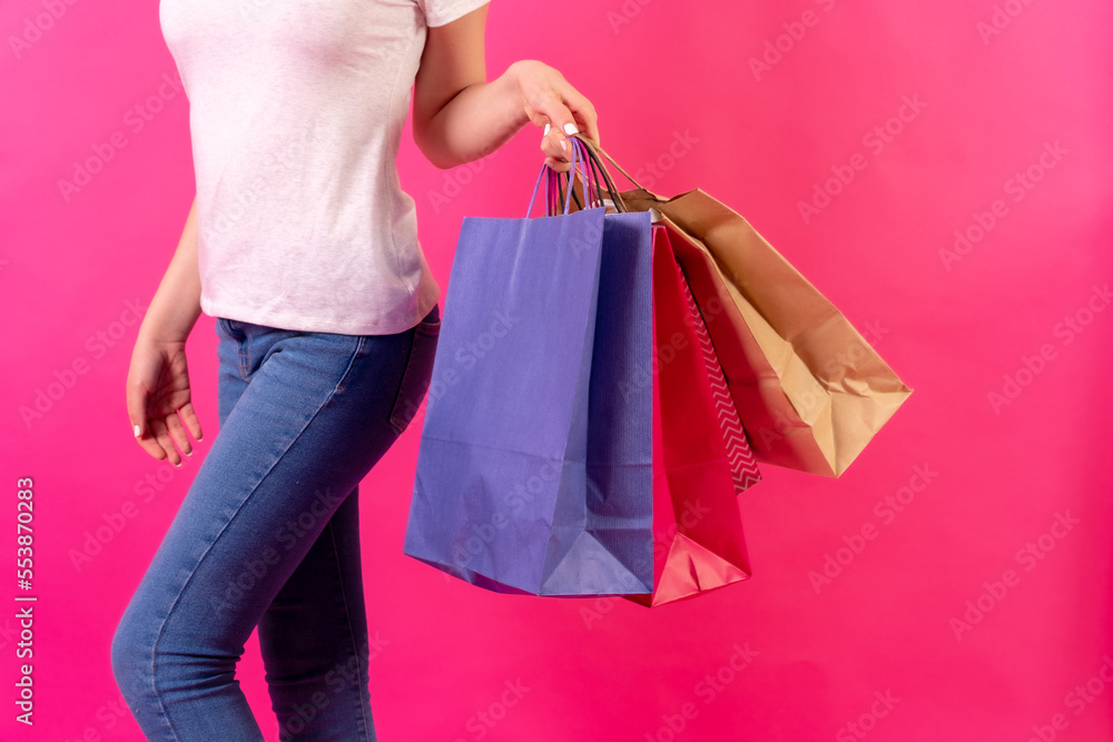Unrecognizable person with shopping bags moving, in studio on pink background