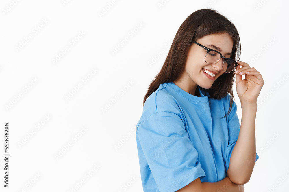 Portrait of beautiful girl in glasses laughing and smiling, standing in blue t-shirt over white background Portrait of beautiful girl in glasses laughing and smiling, standing in blue t-shirt over white background
