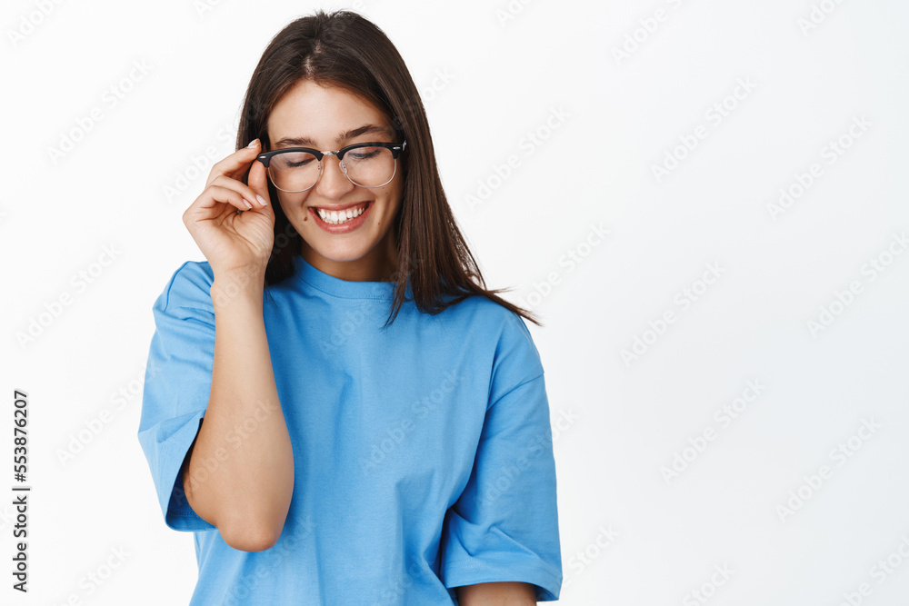 Beautiful young girl student in glasses, trying new eyewear at optic store, standing in blue t-shirt over white background Beautiful young girl student in glasses, trying new eyewear at optic store, standing in blue t-shirt over white background