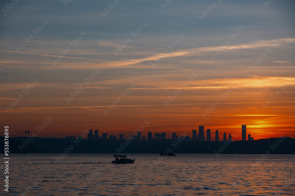 Blue and warm orange colored sky, sunset at the city with fisher boats and cityview, landscape